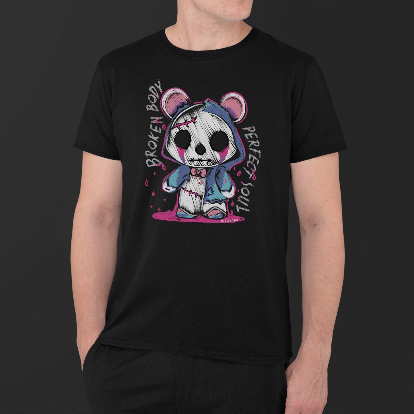 man wearing a black unisex tshirt features a handrawn illustration of an emo-horror-bear with pink blood dropping design and text broken body perfect soul