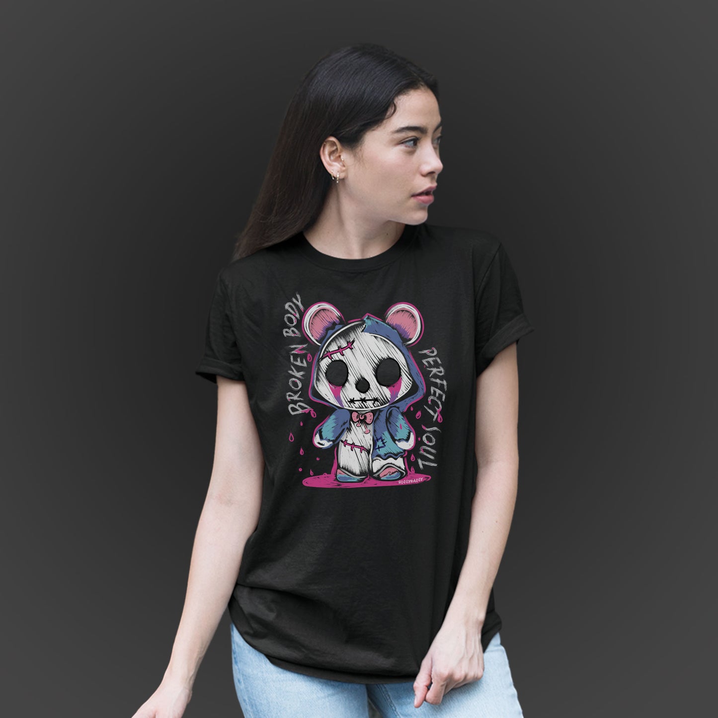 woman wearing a black unisex tshirt features a handrawn illustration of an emo-horror-bear with pink blood dropping design and text broken body perfect soul