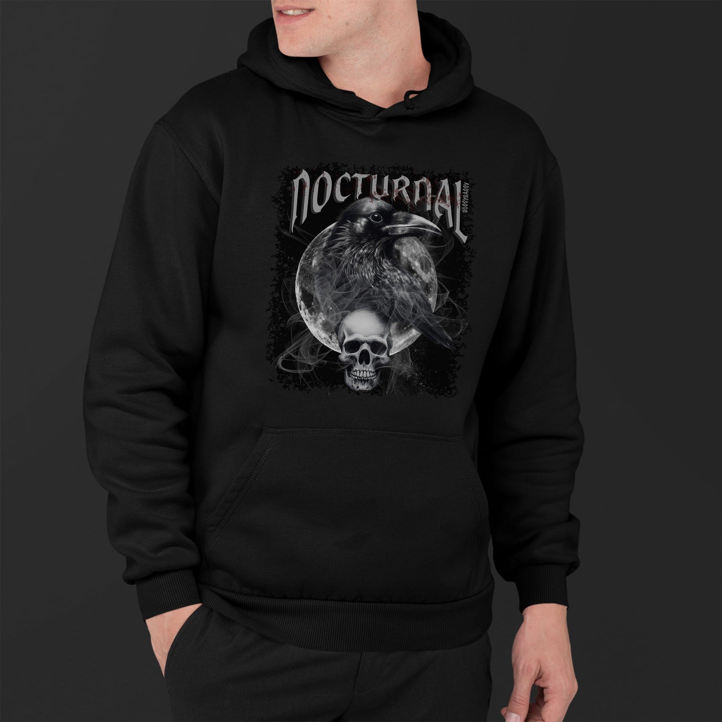 Man Wearing A Black hoodie With An Illustration Of A Raven And Skeleton At Night Time With A Skull Under Full Moon