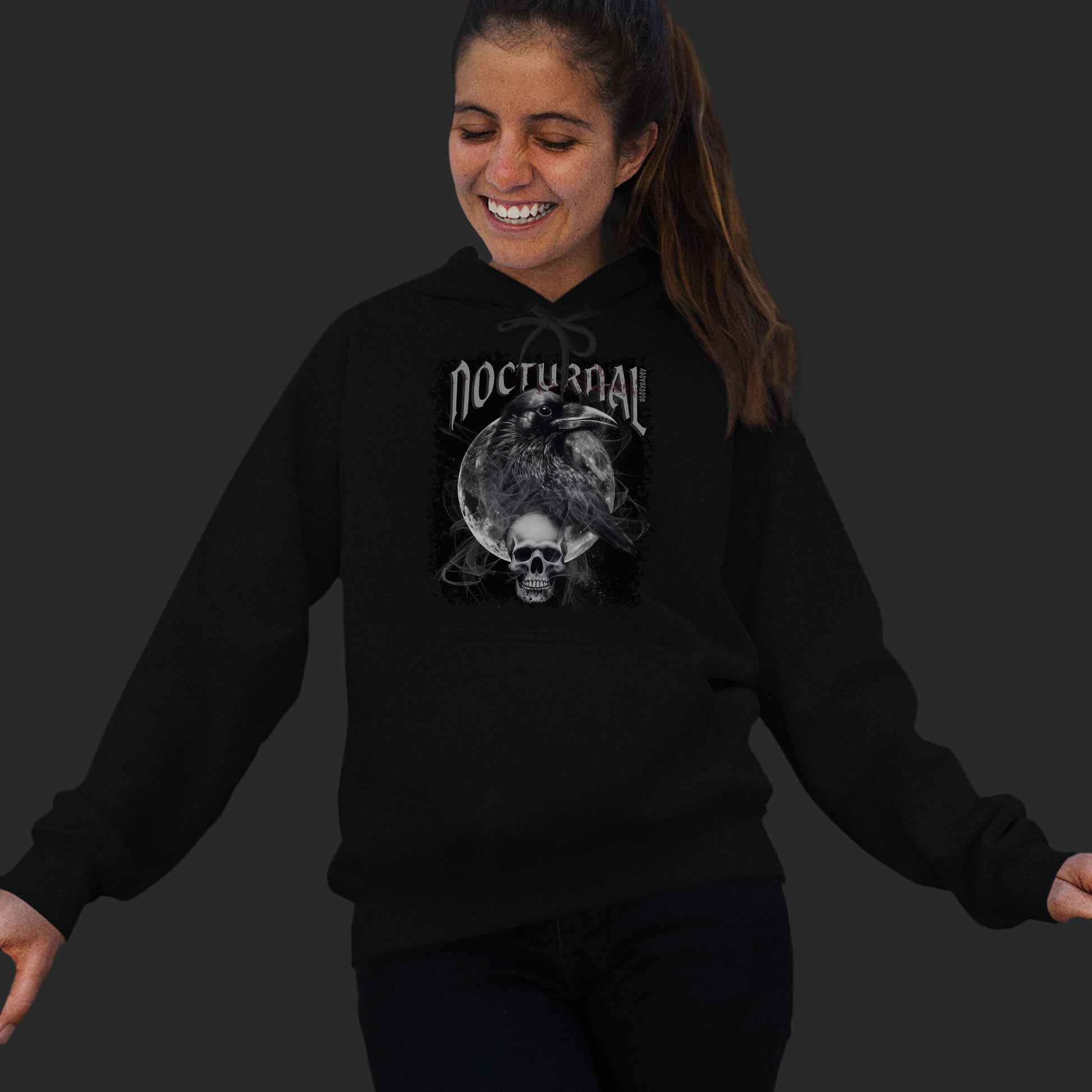 Woman Wearing A Black hoodie With An Illustration Of A Raven And Skeleton At Night Time With A Skull Under Full Moon